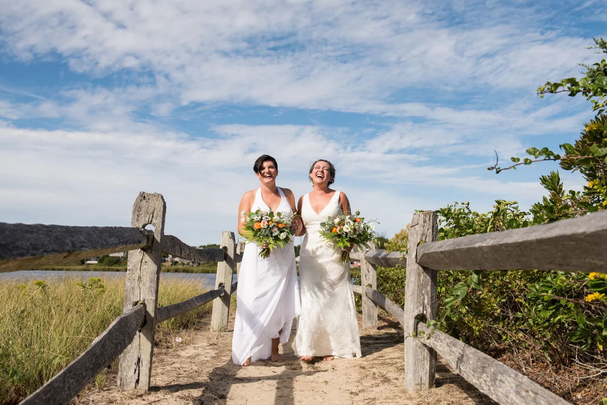 Two brides laughing together outside by a lake Leise Jones Photography Boston MA