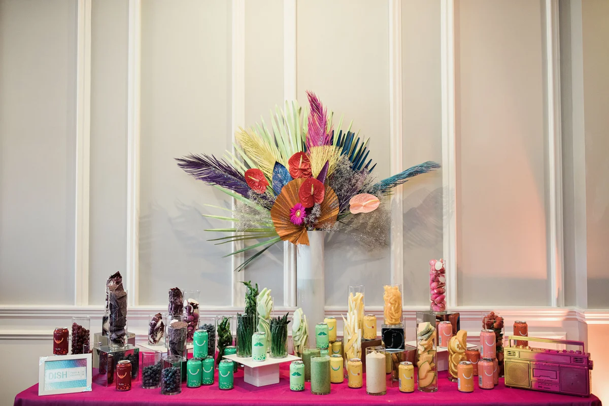 80s themed pride party brooklyn new york table with beverages matching color spectrum theme with vase of bright flowers in middle