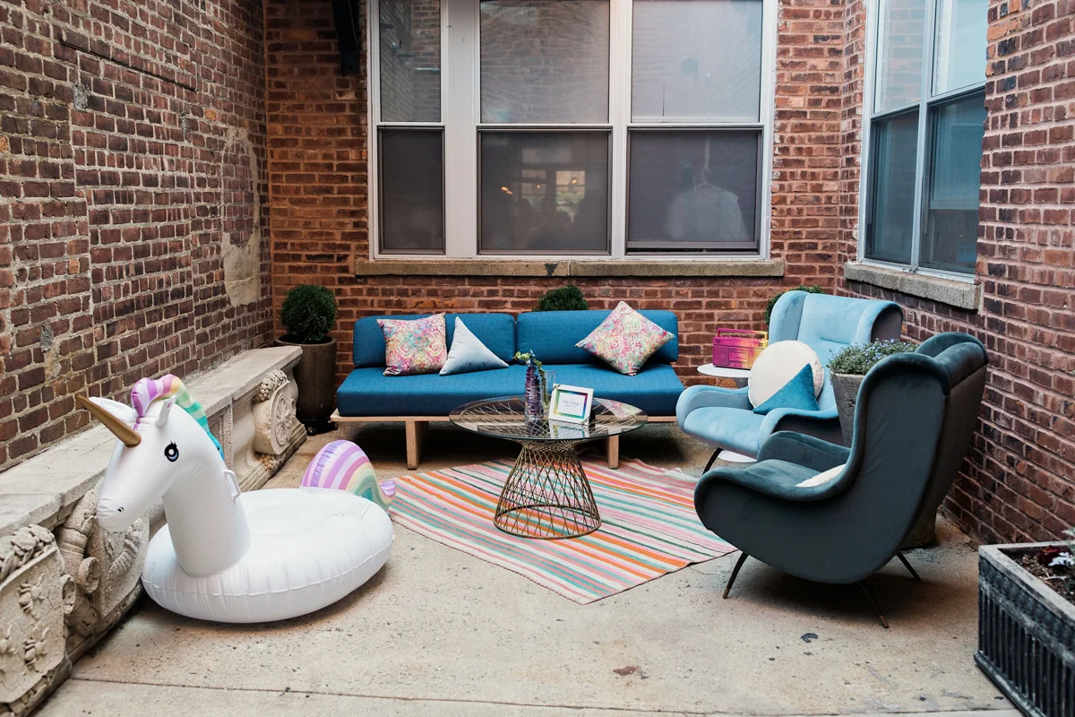 80s themed pride party brooklyn new york outside area with chairs, sofa, and inflatable unicorn float