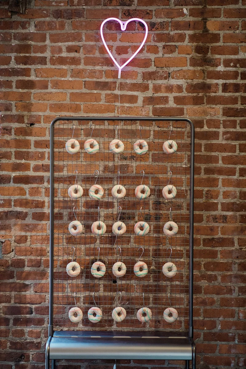 80s themed pride party brooklyn new york donuts on hooks with heart-shaped neon sign above