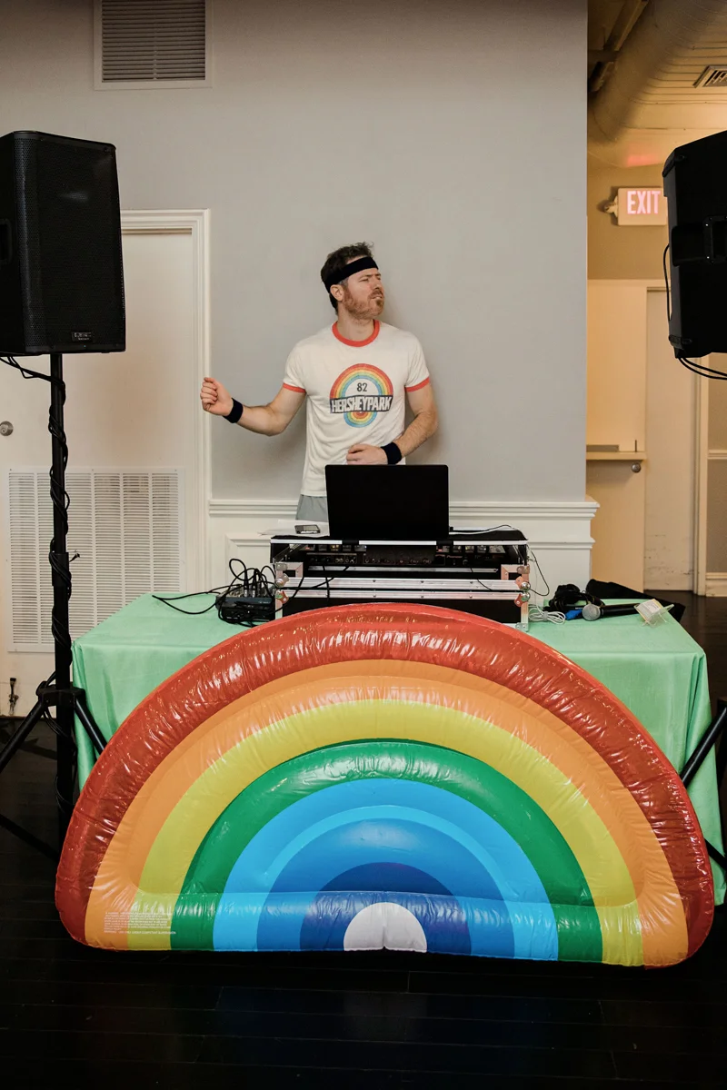 80s themed pride party brooklyn new york dj rob kelley at table with inflatable rainbow in front