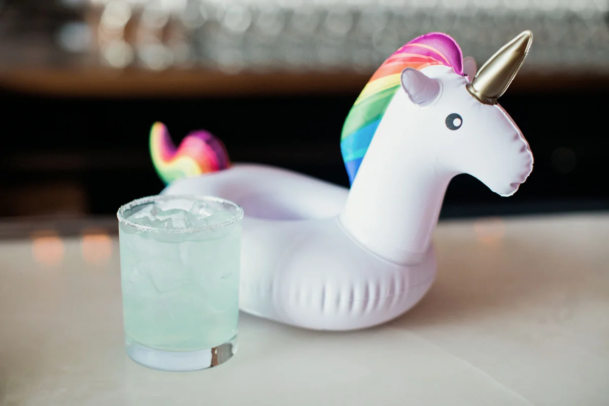 80s themed pride party brooklyn new york “it’s electric” drink next to unicorn drink floaty on table