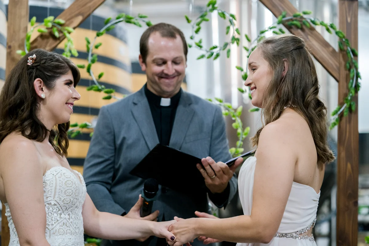 Brewery wedding washington D.C. brides holding hands during ceremony