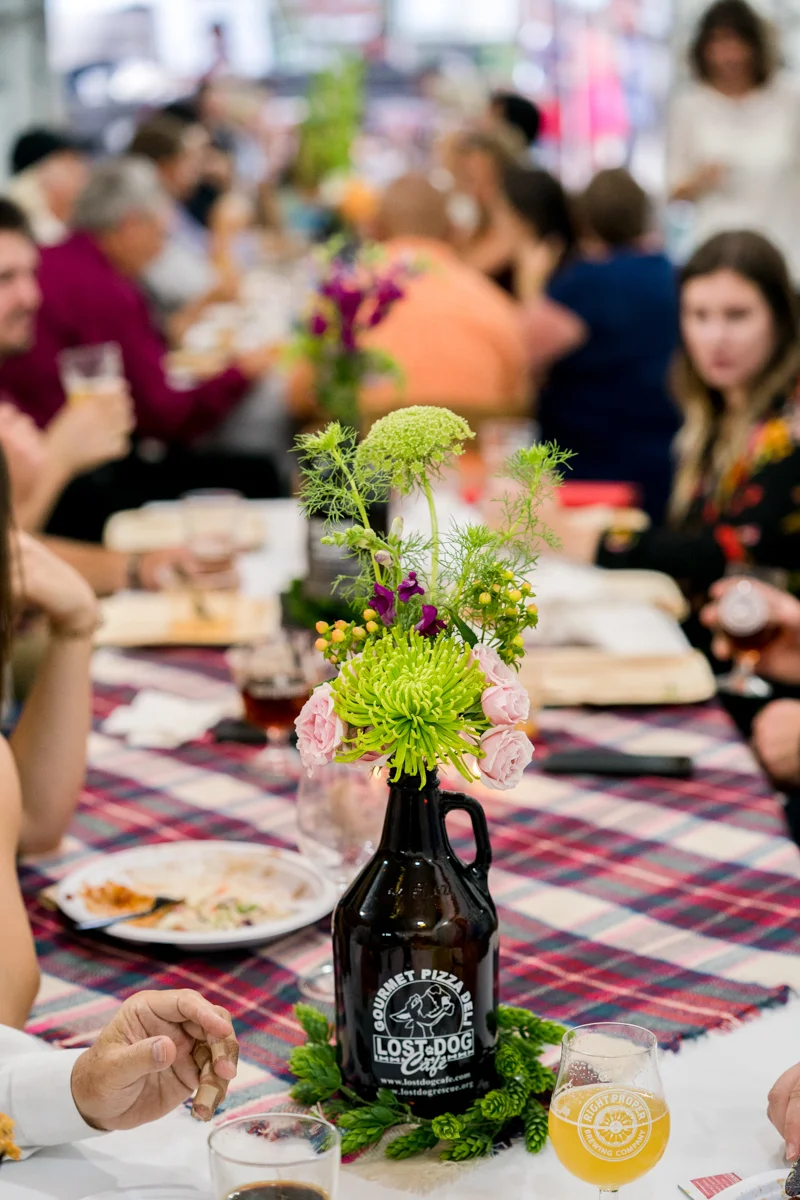 Brewery wedding washington D.C. guests at long tables with floral centerpieces in beer growler