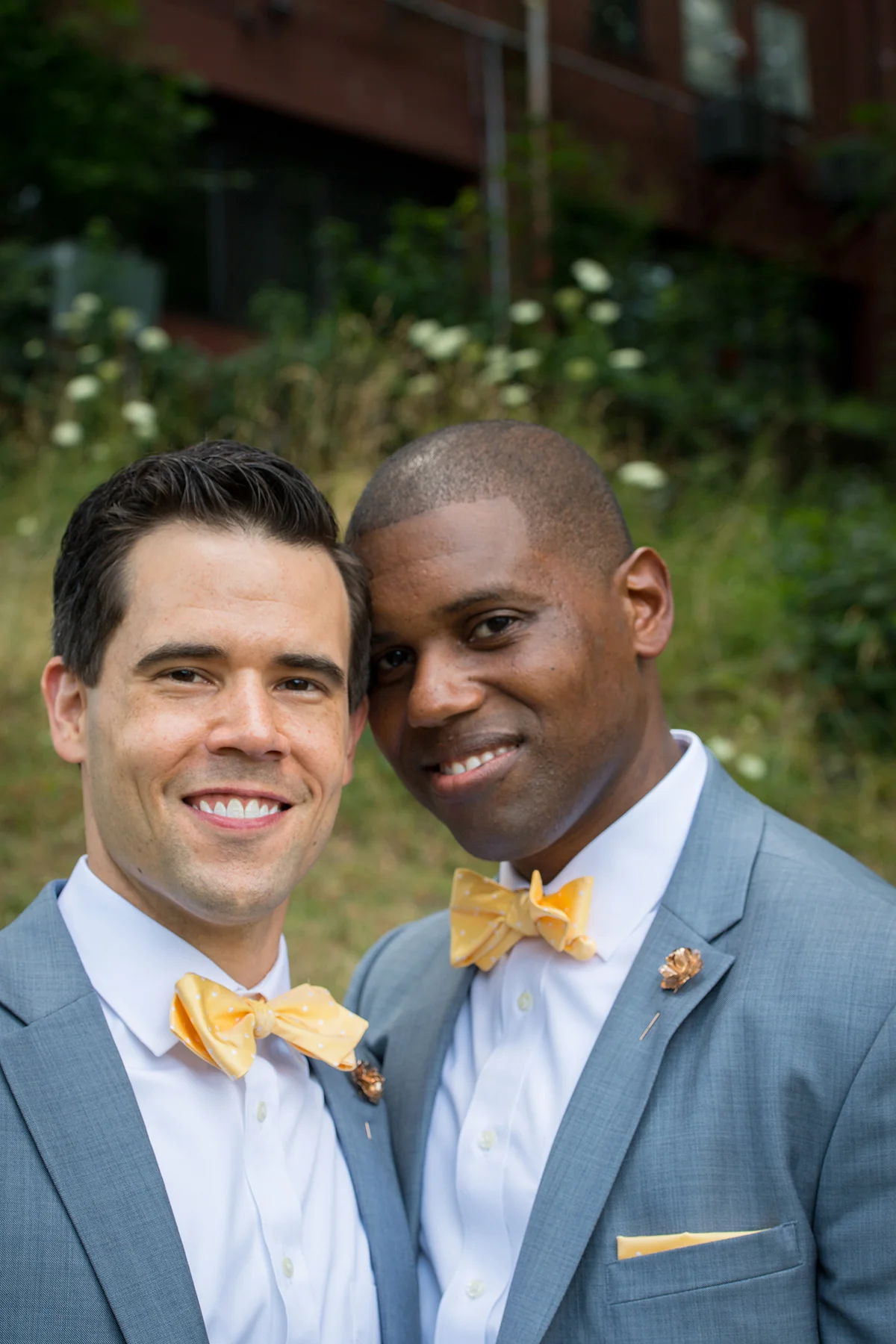 two grooms smiling at the camera with their heads together michelle schapiro photography