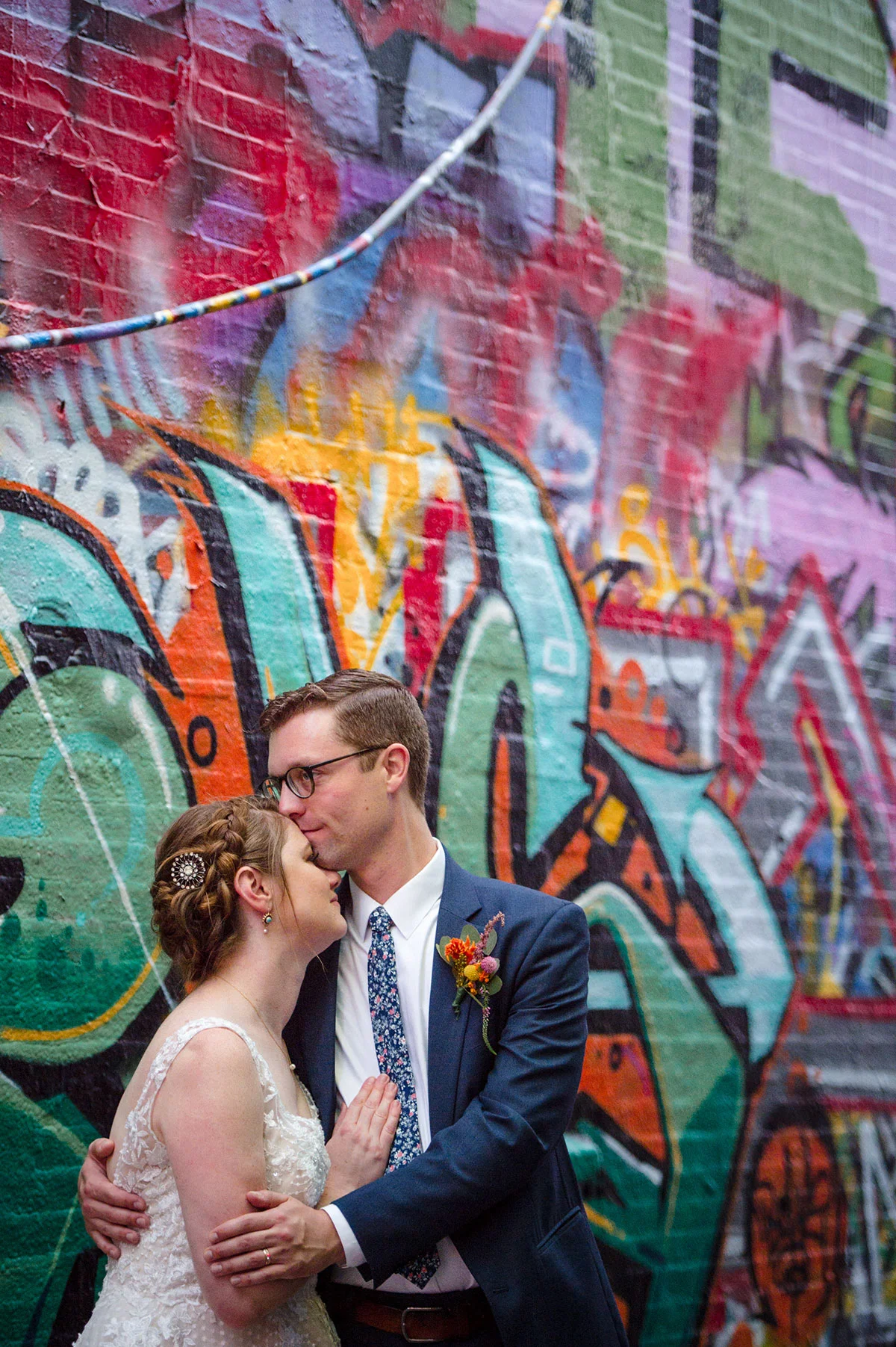 bride and groom embracing for portrait in front of mural wall michelle schapiro
