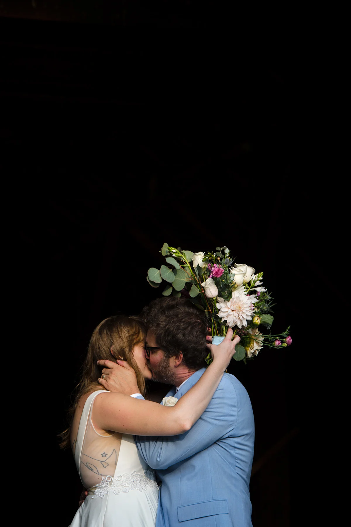 couple kissing after their wedding with dark background michelle schapiro photography