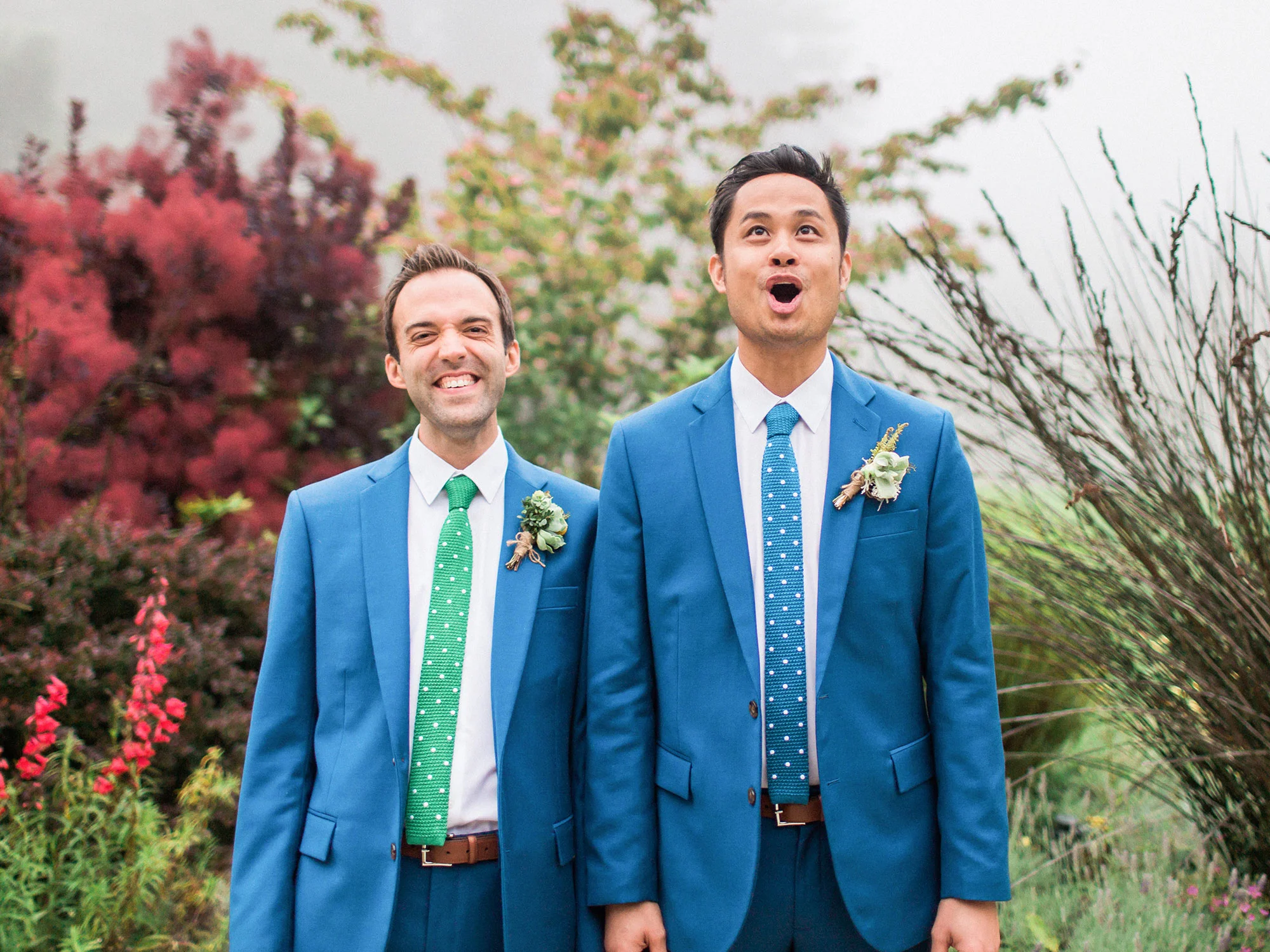 two grooms in matching suits holding hands and smiling at their wedding Apollo Fotografie San Francisco