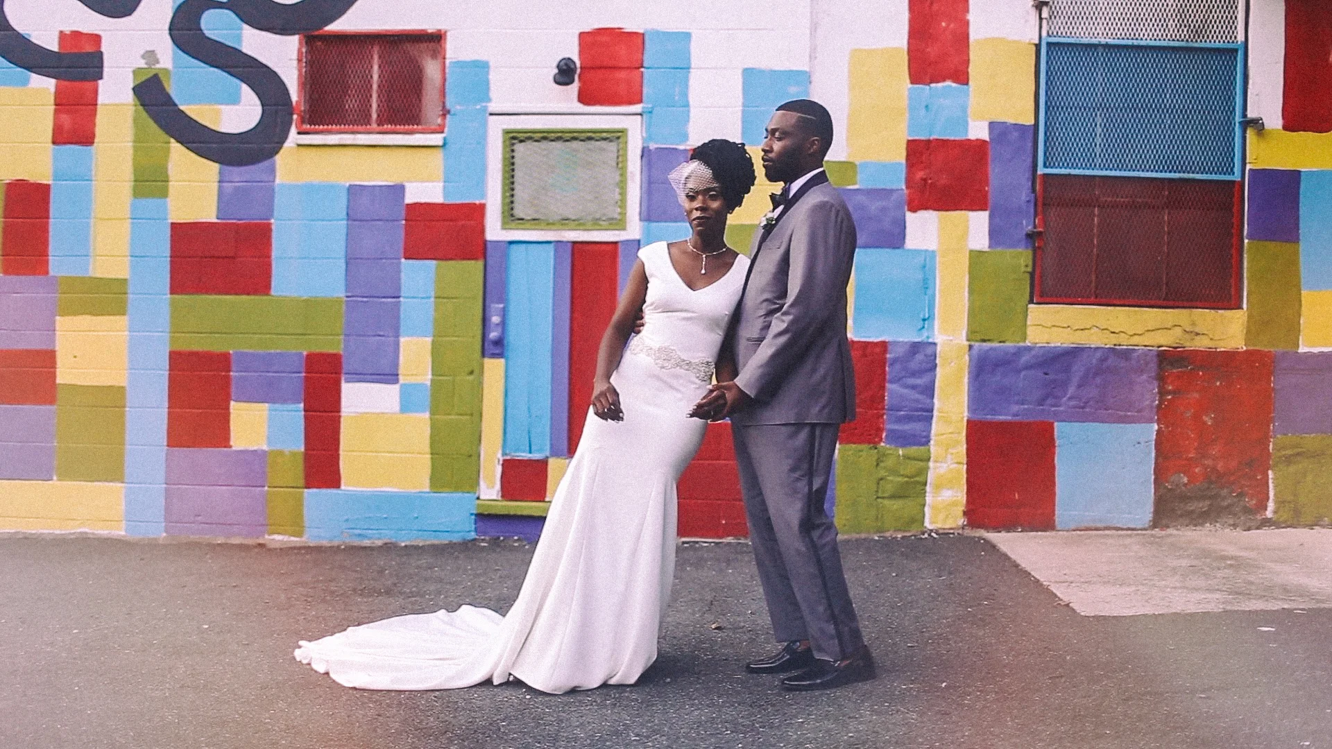 Bride leaning on groom posing in front of colorful mural Philly PA Love More Films