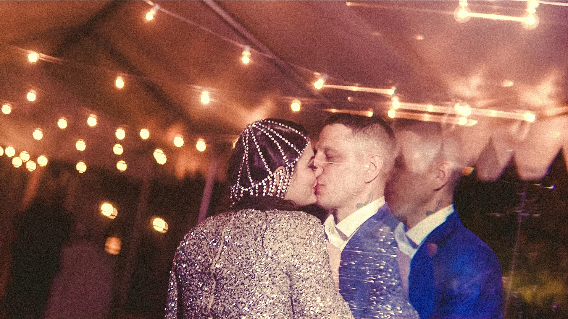 Newlywed couple kissing under reception tent lights Philadelphia PA Love More Films