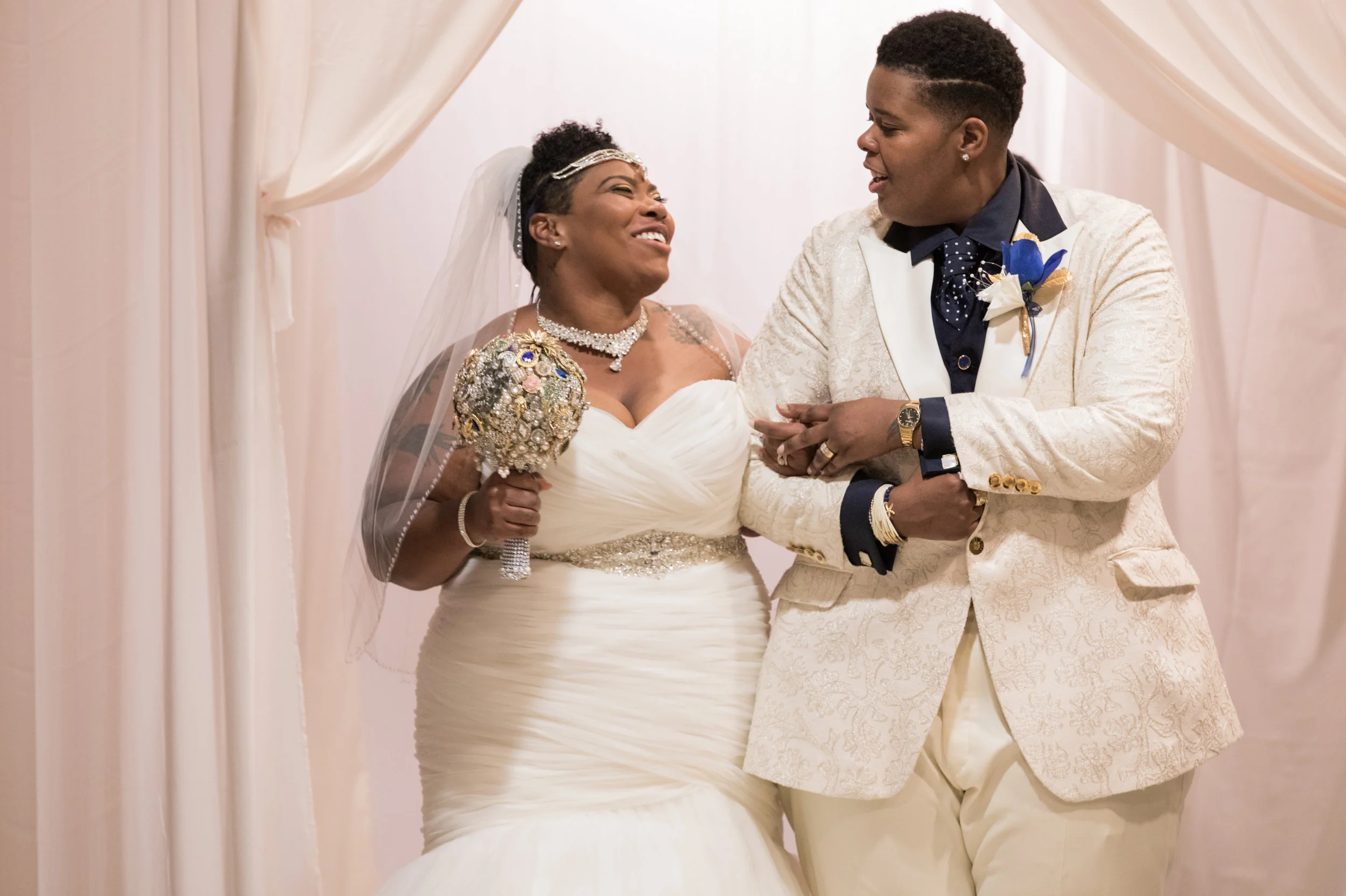 newlywed couple walking into wedding reception arm in arm and smiling at each other with jeweled bouquet Meera Graham Photography Missoula Montana