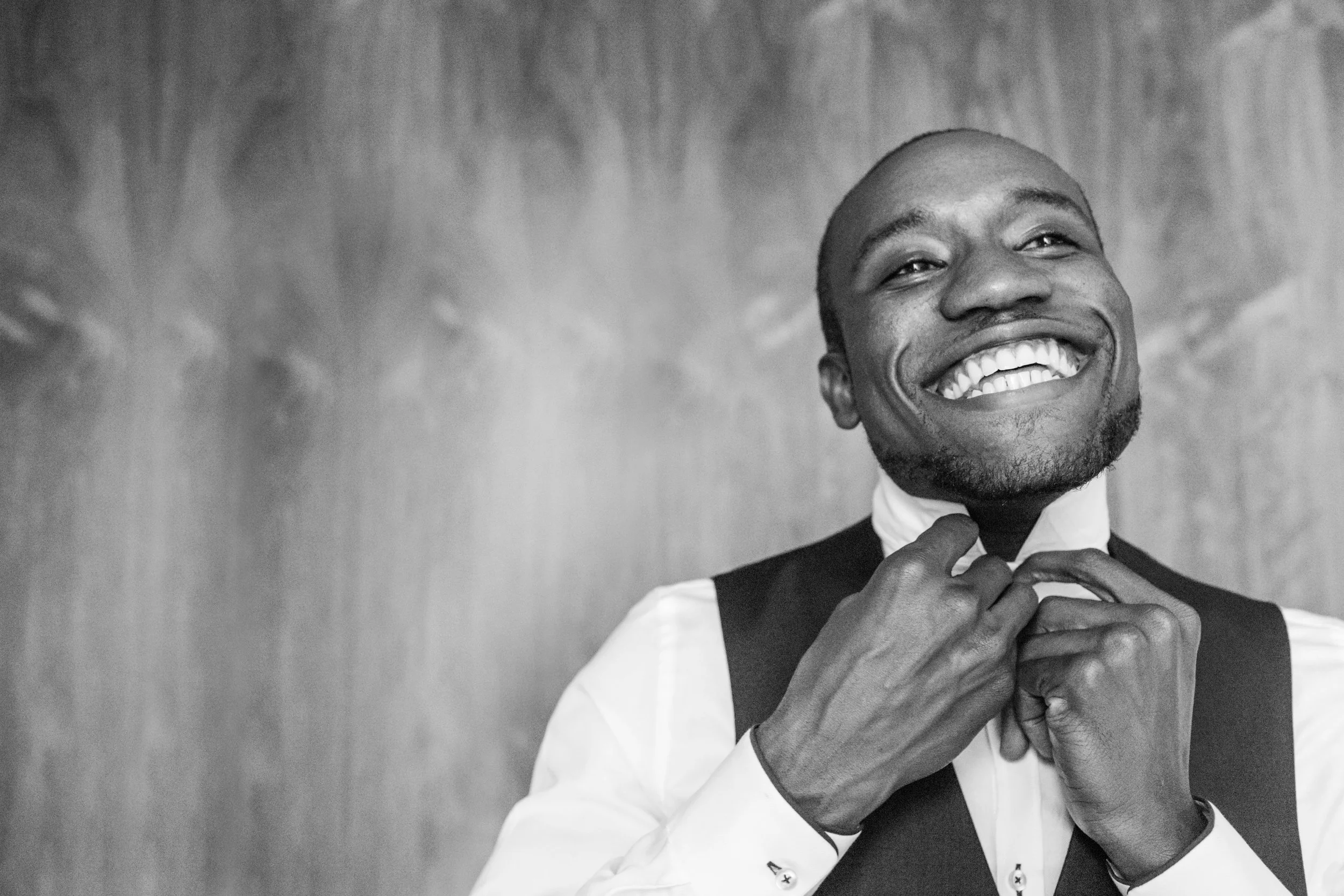 groom smiling wide and adjusting his collar and tie before his wedding ceremony Meera Graham Photography Missoula Montana