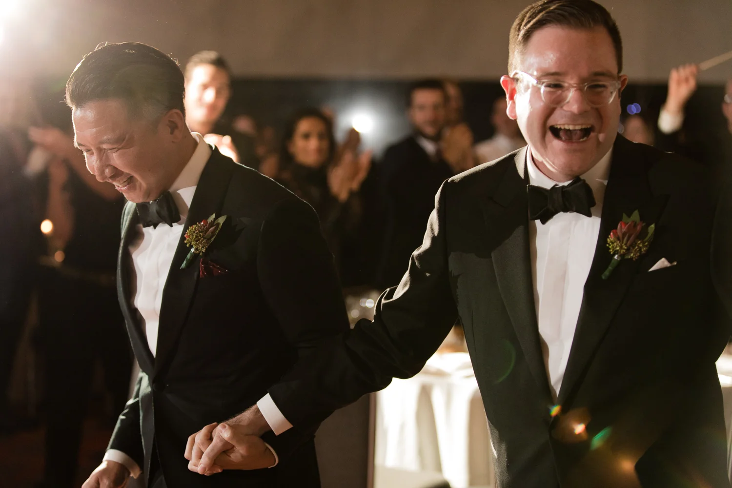 two grooms smiling and laughing while walking into their wedding reception Meera Graham Photography Missoula Montana