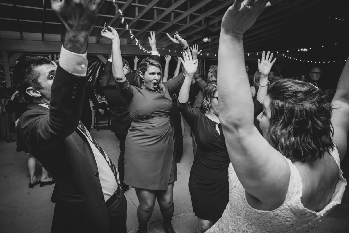 Romantic, Intimate-Feeling Wedding bride and guests on dance floor with arms in the air