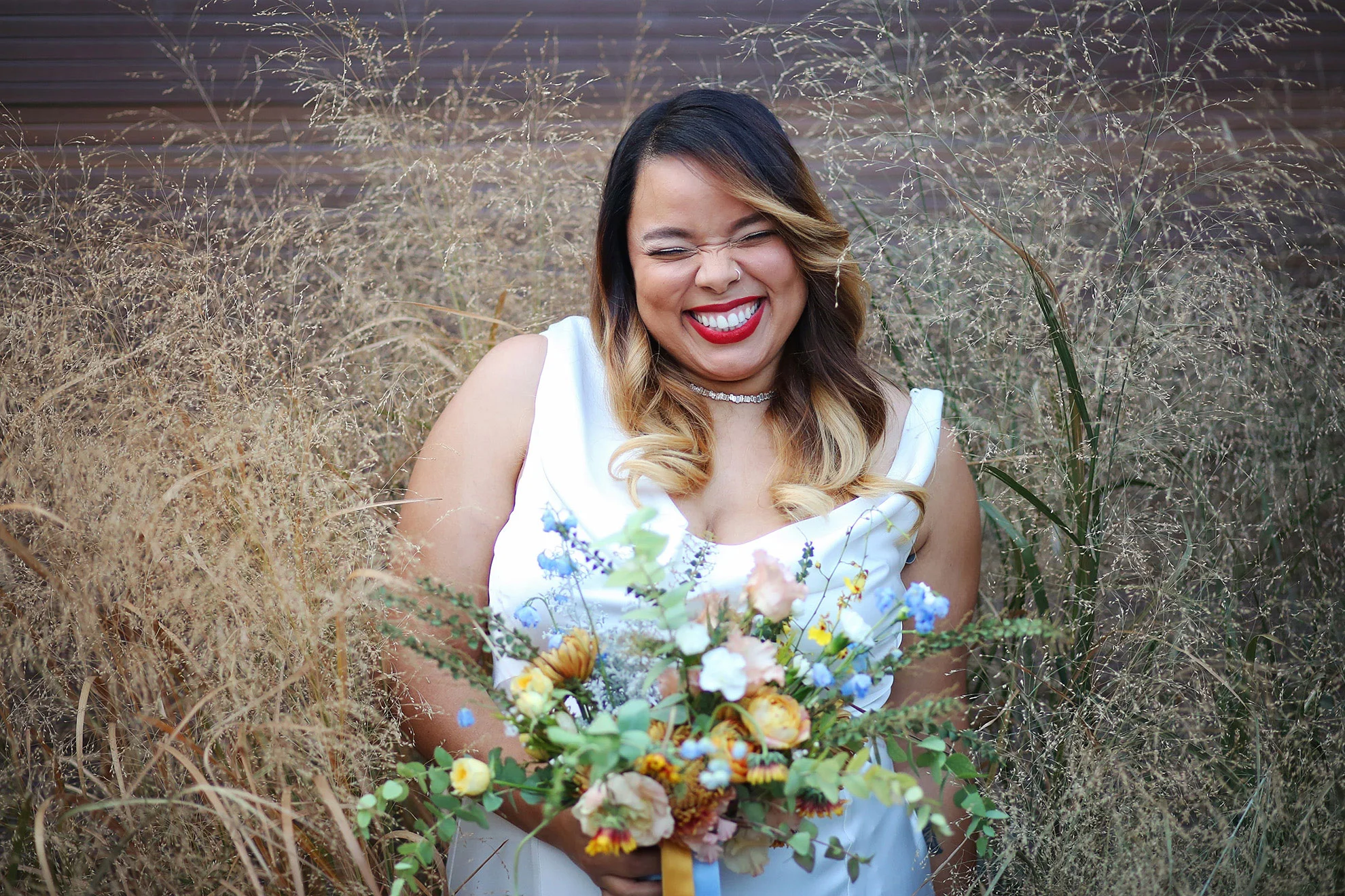 Smiling bride in wedding dress holding blue bouquet