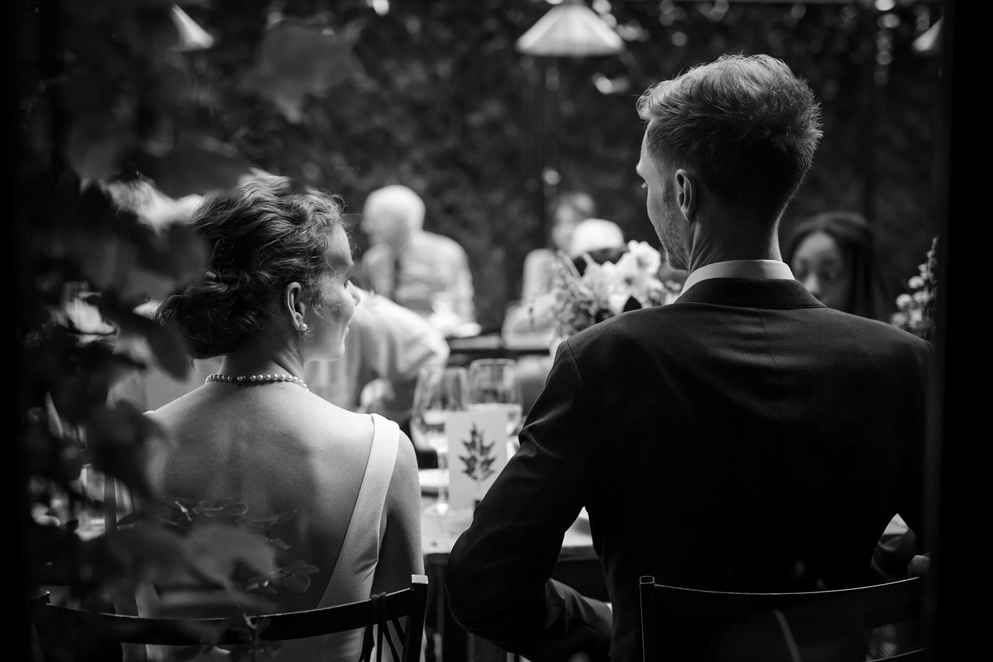 newlywed bride and groom staring at each other while sitting at their head table at their wedding reception
