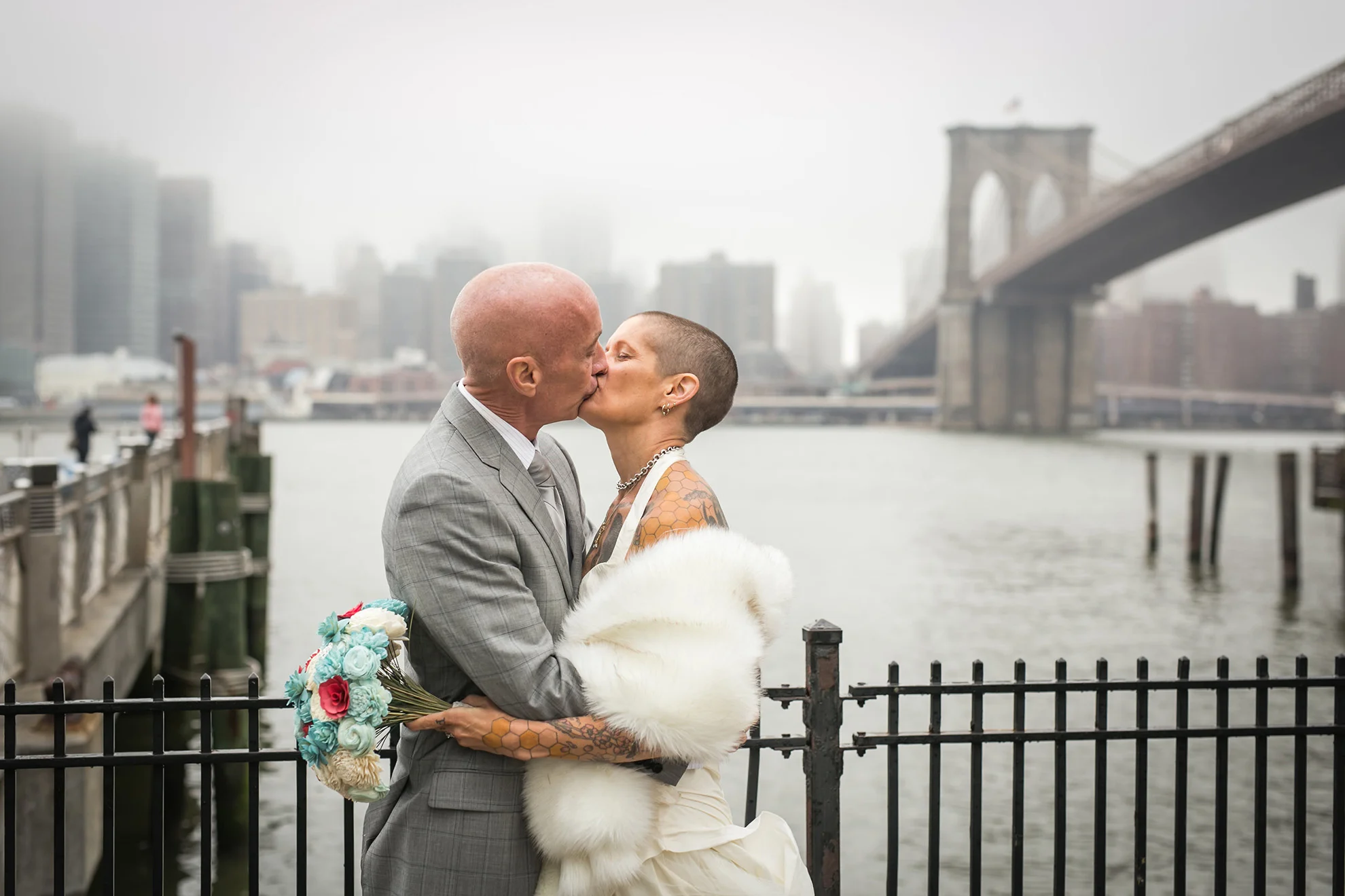 newlywed tattooed couple sharing a kiss right after their wedding elopement with brooklyn bride in backgroun