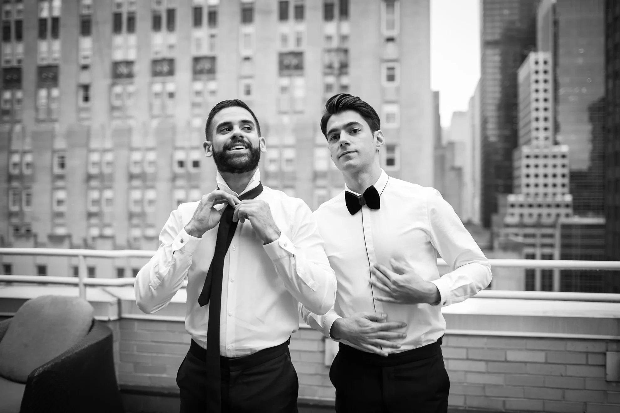 two grooms adjusting their ties and smiling at the camera at nyc wedding