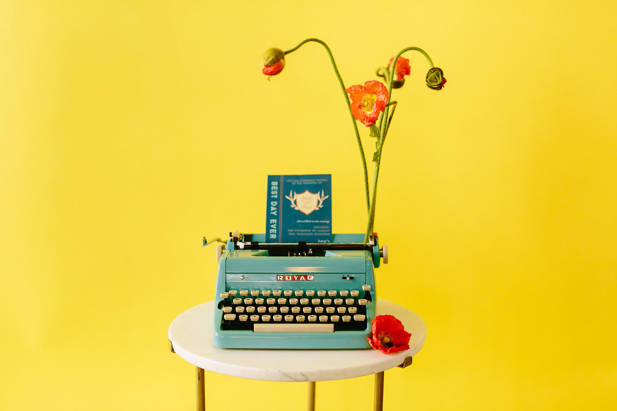 wes anderson inspired wedding brooklyn new york typewriter with invitation against bright yellow background