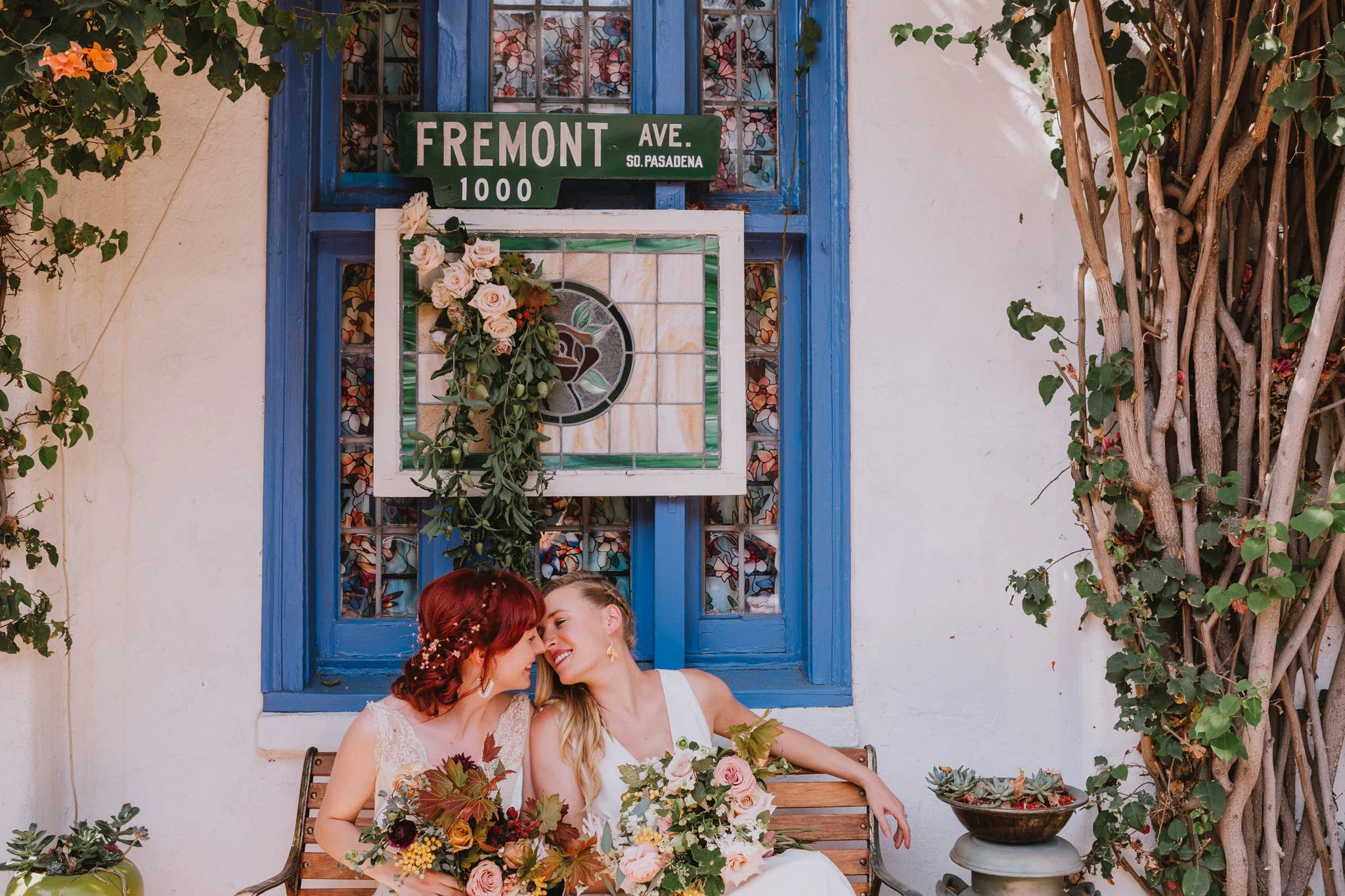 two brides lean in for kiss in front of stained glass window at wedding reception by Rebecca y Las Otras Photography