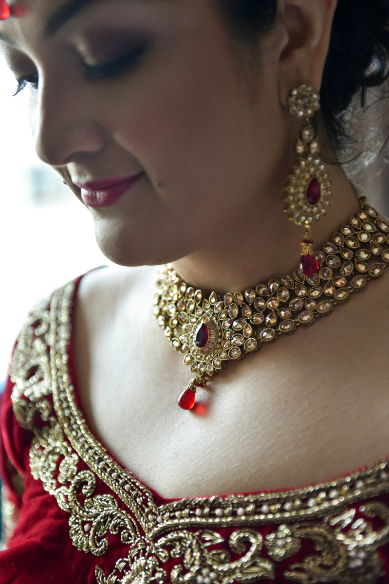 Mita dressed for the Indian wedding ceremony in her gold and red necklace, earrings and sari