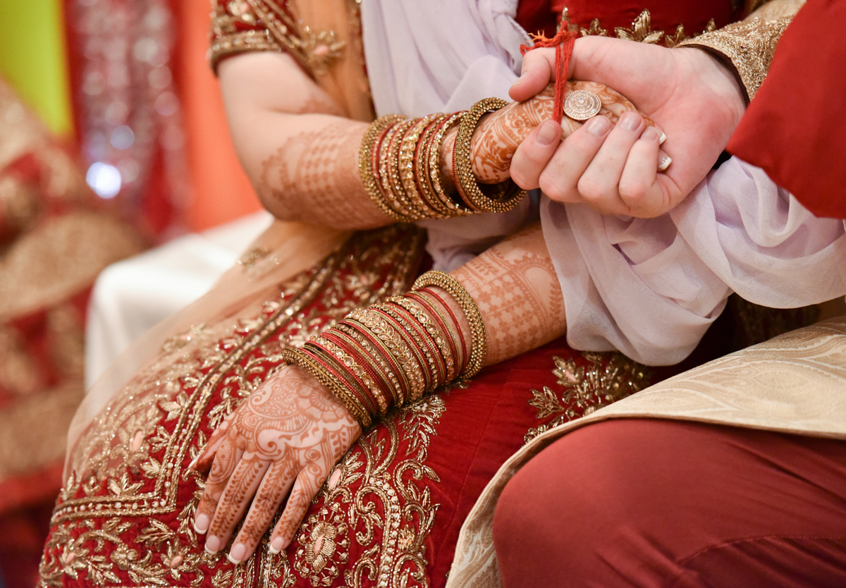 Mita and James seated and holding hands as part of their Indian wedding ceremony in Hong Kong