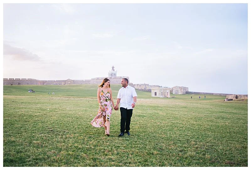 couple walks across open field for wedding engagement session Sharma Shari Puerto Rico Wedding Photographer