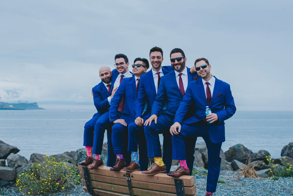 Persian-Canadian Wedding Innocent Thunder Photography Sooke Victoria Canada amin and groomsmen standing on bench showing off colorful socks