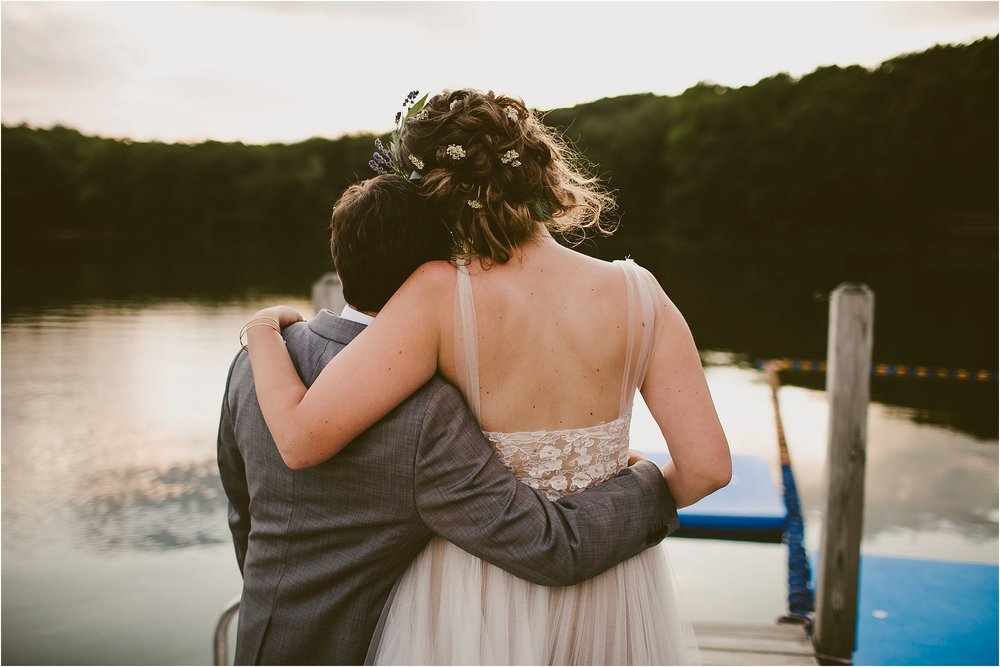 bride and groom hug by lake at diy wedding in the woods Emily Dykema
