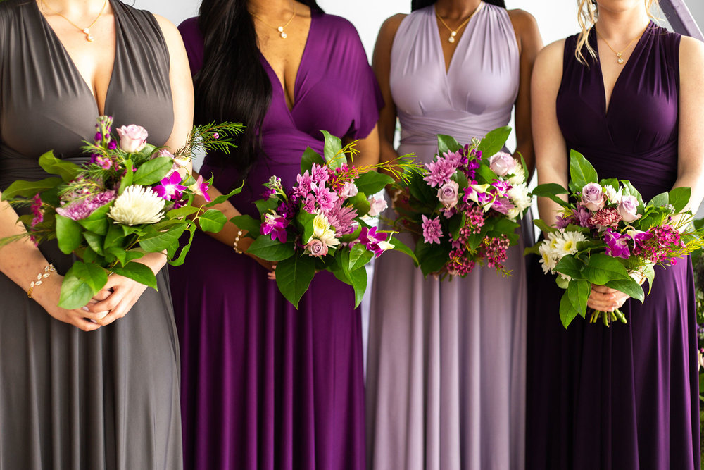 Henkaa fall wedding party dresses in purple and gray tones with bridesmaids holding bouquets