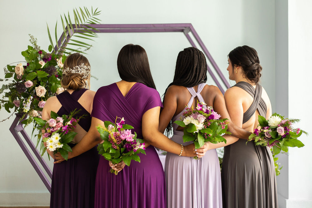 Henkaa fall wedding party dresses in purple and gray tones with bridesmaids holding bouquets