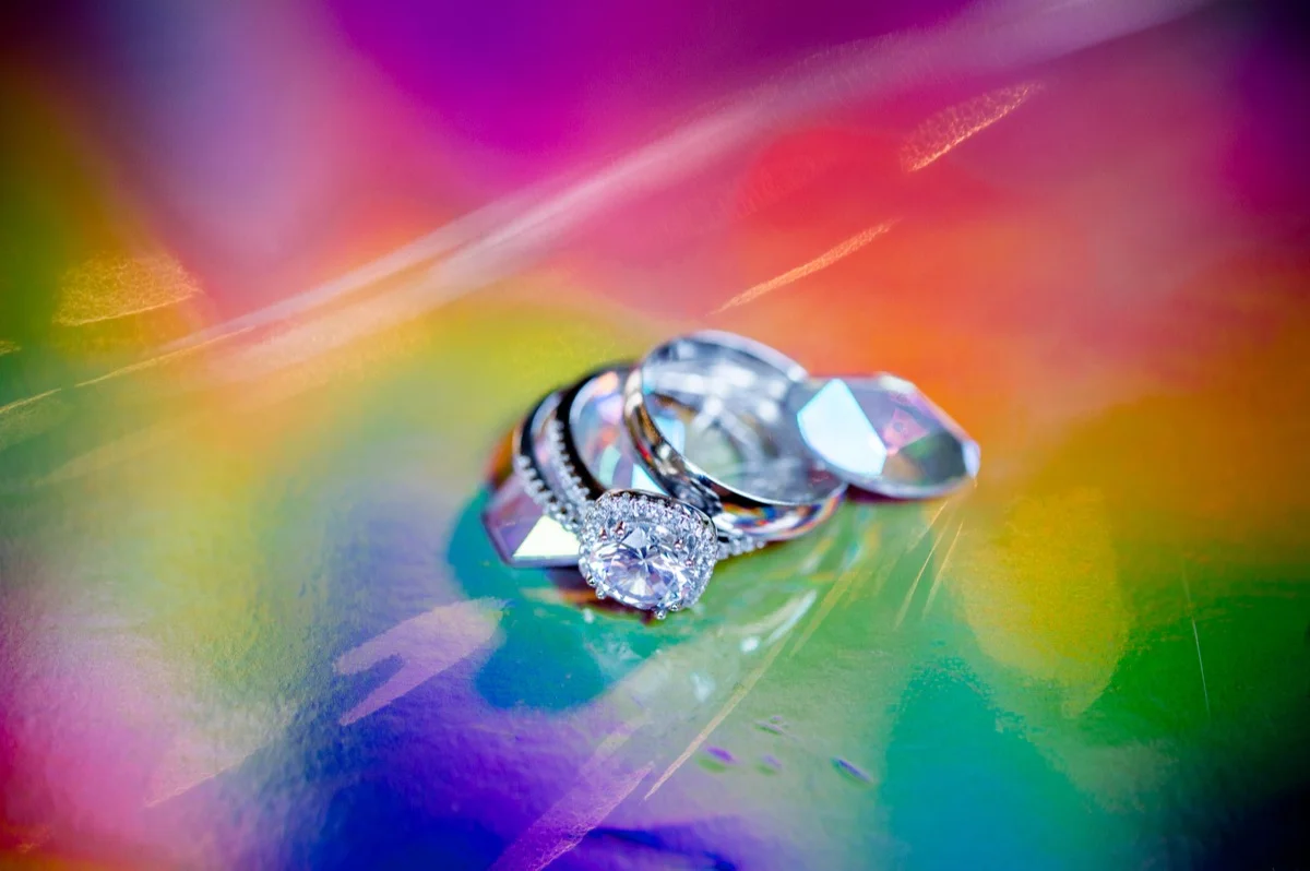 RAINBOW QUEER WEDDING INSPIRATION MICHELLE SCHAPIRO, DEANNA NAGLE, RINGS ON IRIDESCENT RAINBOW SURFACE