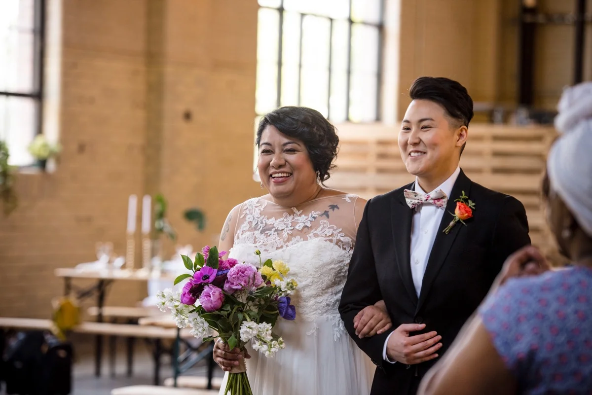 RAINBOW QUEER WEDDING INSPIRATION MICHELLE SCHAPIRO, DEANNA NAGLE, couple walking down aisle with arms linked