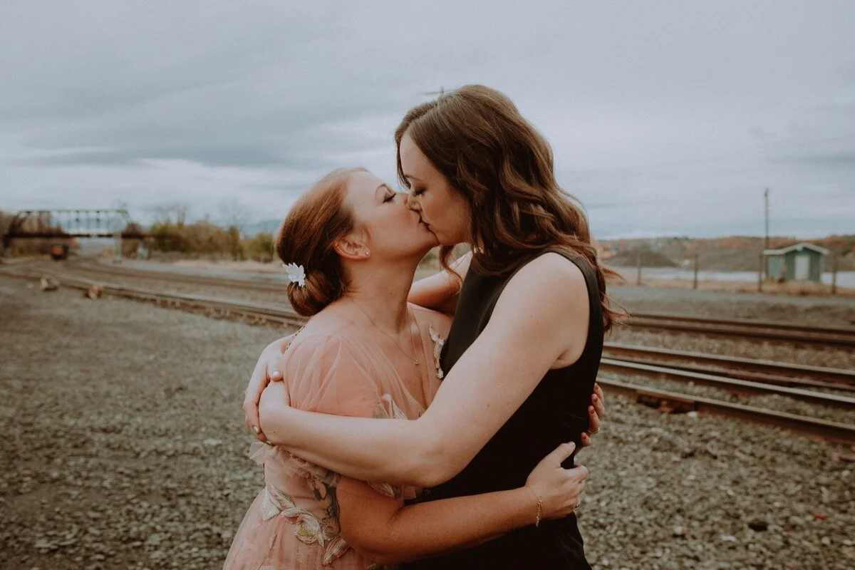newlywed brides kiss near old train tracks before industrial wedding ceremony in Hudson New York Chellise Michael Photography
