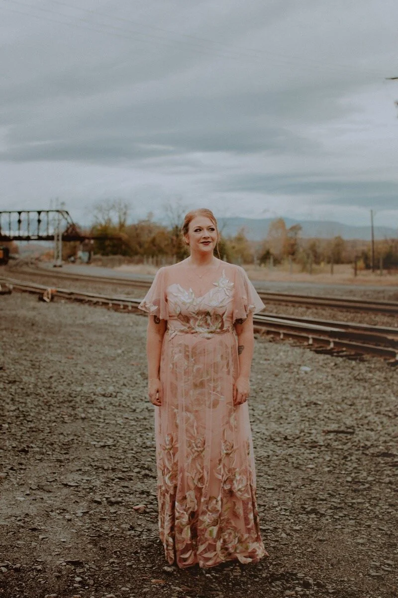 bride in pink lace chiffon dress near old train tracks before industrial wedding ceremony in Hudson New York Chellise Michael Photography