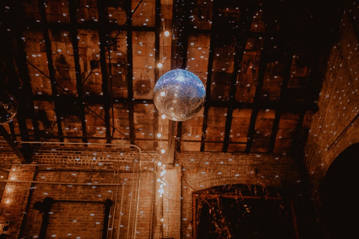 Disco ball over dance floor at reception at industrial wedding venue in Hudson New York Chellise Michael Photography