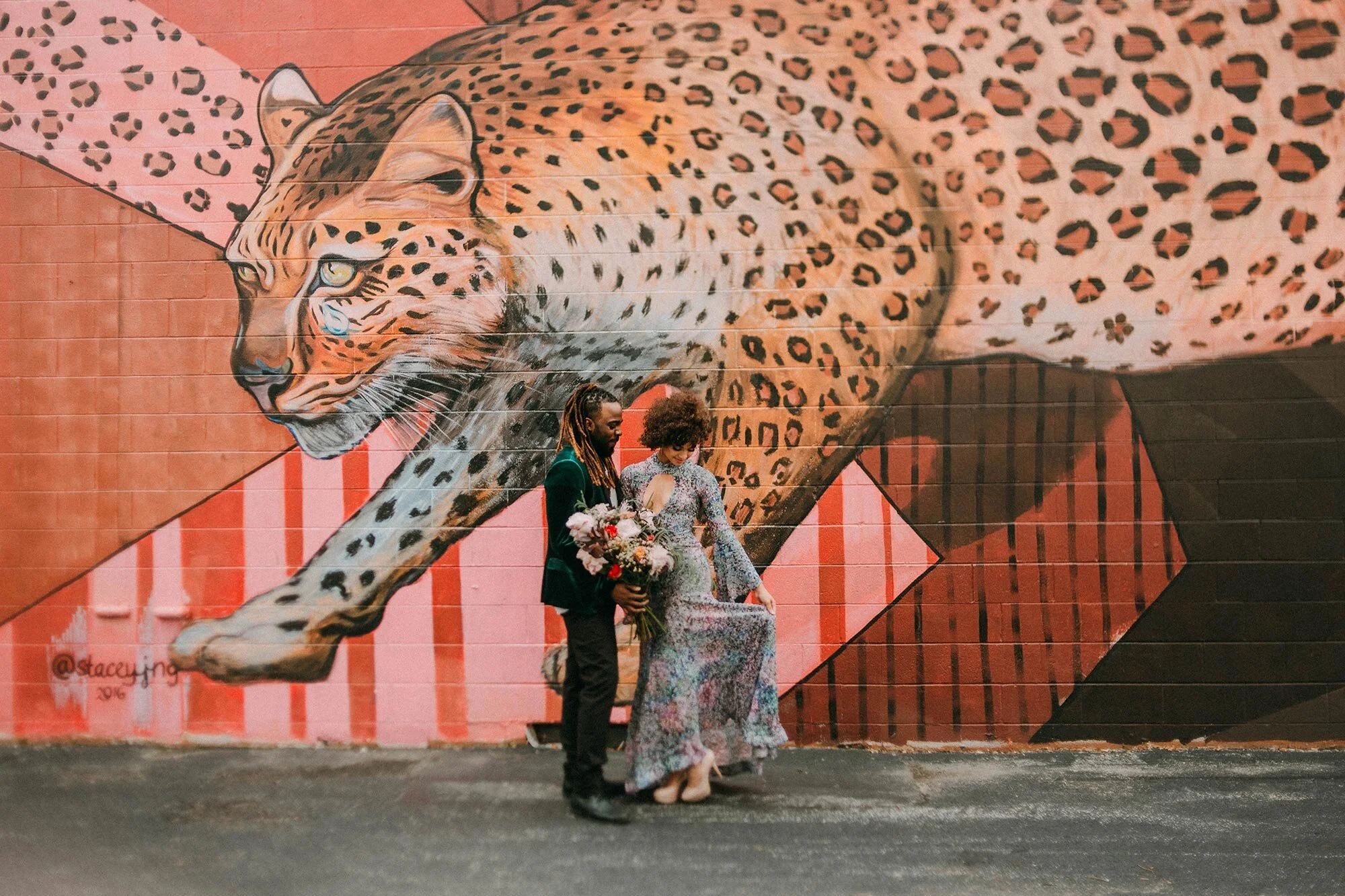 bride in sequin dress and groom in green velvet suit in front of leopard mural Milwaukee A Lentz Photography