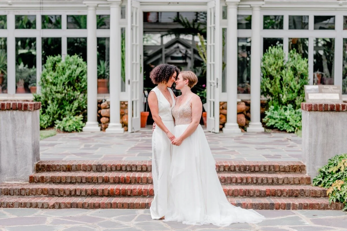 Celestial and Geode wedding inspiration in Winston Salem NC showing two brides in wedding dress and jumpsuit in front of greenhouse Ariel Kaitlin Photography