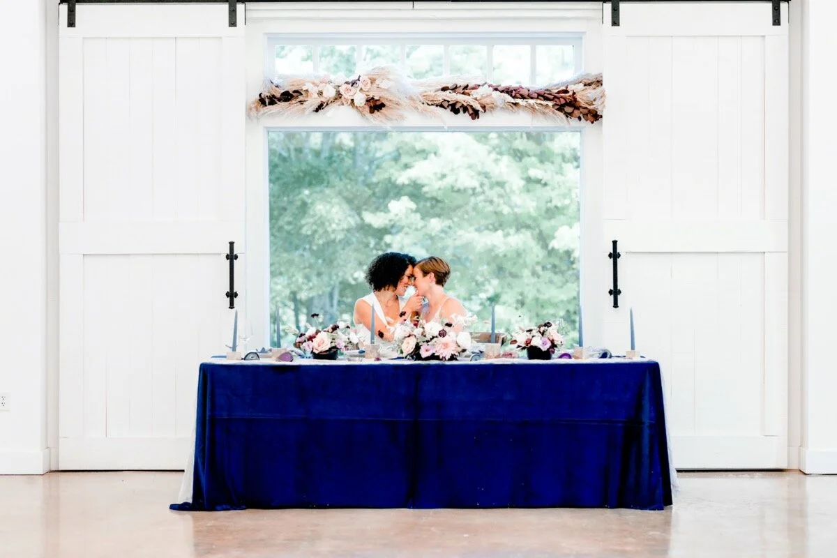 Celestial and Geode wedding inspiration in Winston Salem NC showing two brides leaning in for kiss at head reception table Ariel Kaitlin Photography