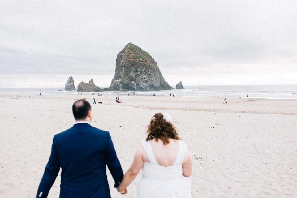 Couple walks towards water on beach holding hands on Washington Coast Fuck Yeah Weddings