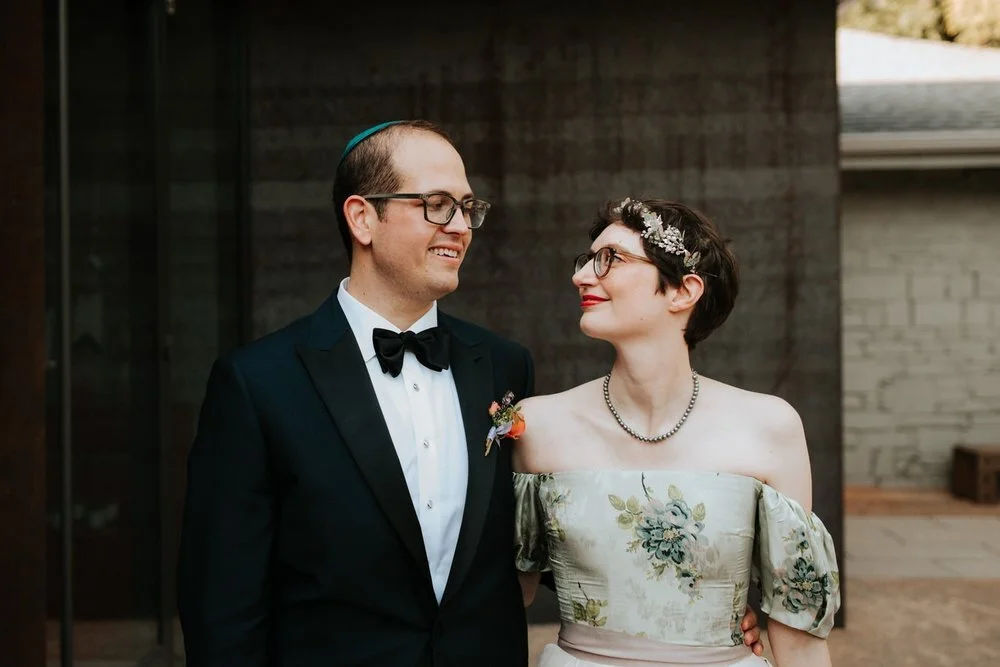 Newlyweds smile at each other in front of venue Engaged couple sit under tree during fall photo session Diana Ascarrunz Austin Texas Wedding Photographer