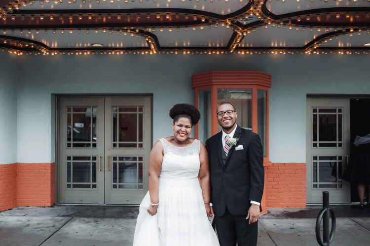 Newlywed couple hold hands and smile in front of old movie theater Richmond Virginia Betty Clicker Photography