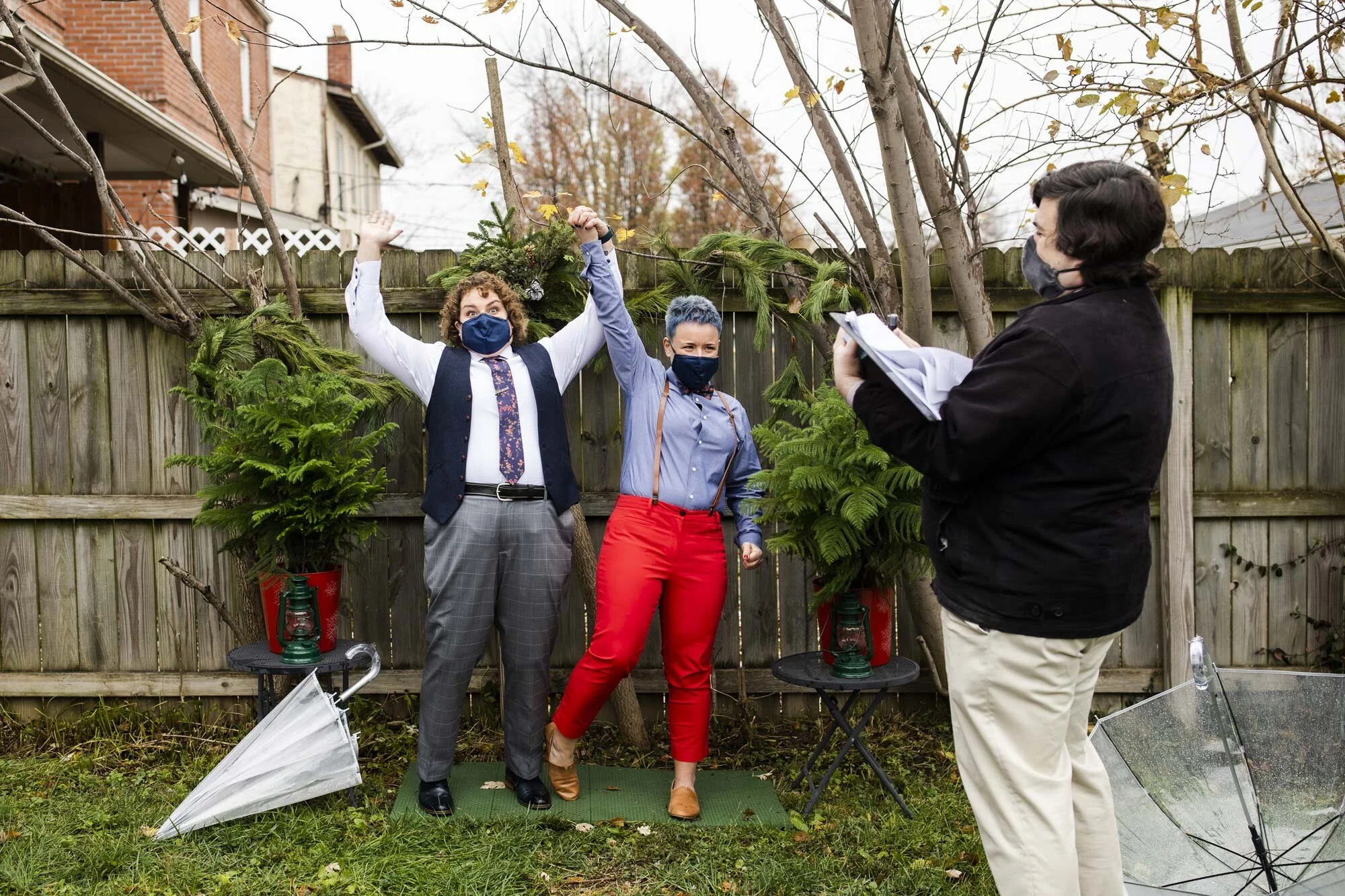 Couple holds hands and jumps into air during backyard wedding ceremony in Ohio Amy Ann Photography