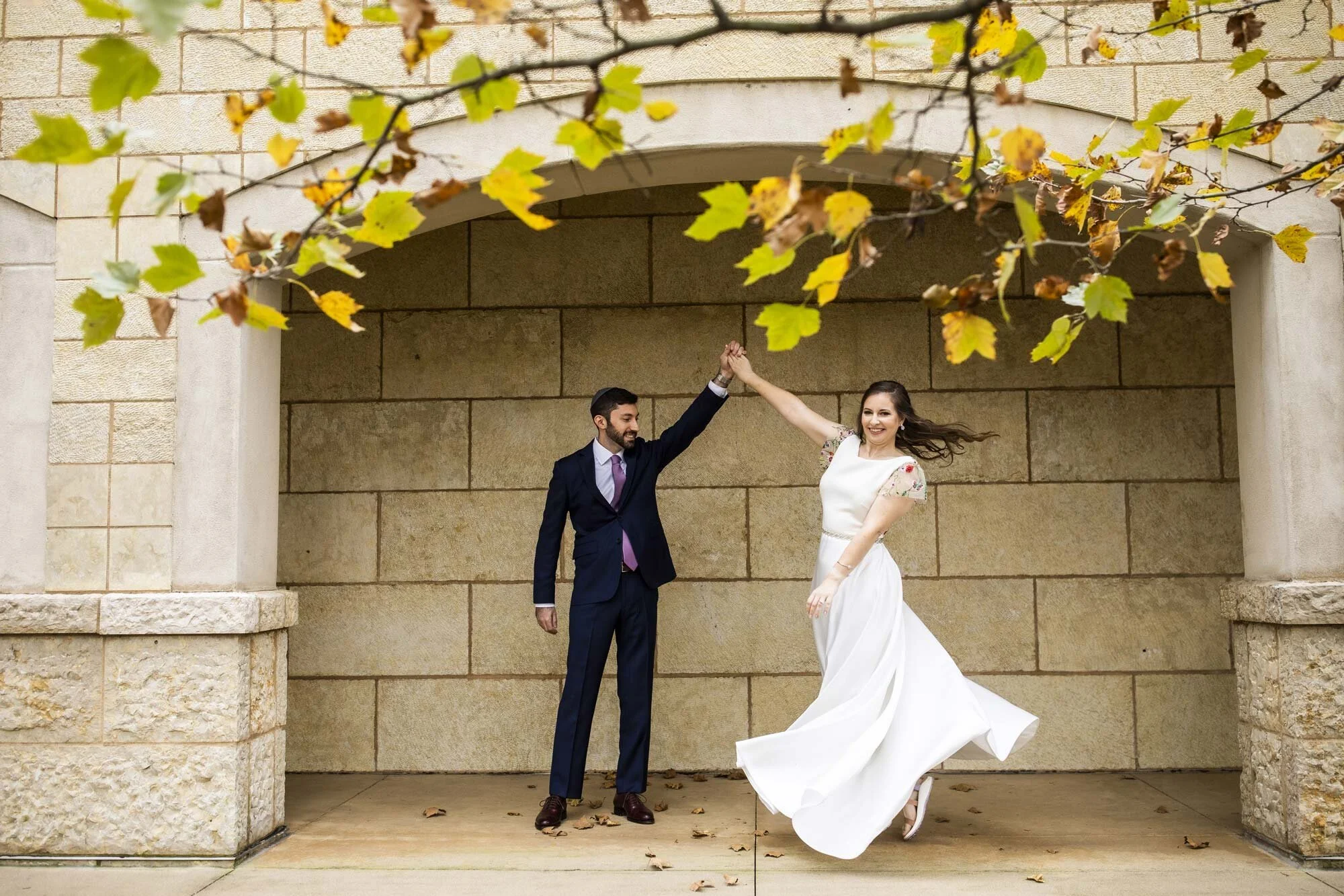 Couple dances and spins in suit and wedding dress in alcove before autumn ceremony in Ohio Amy Ann Photography