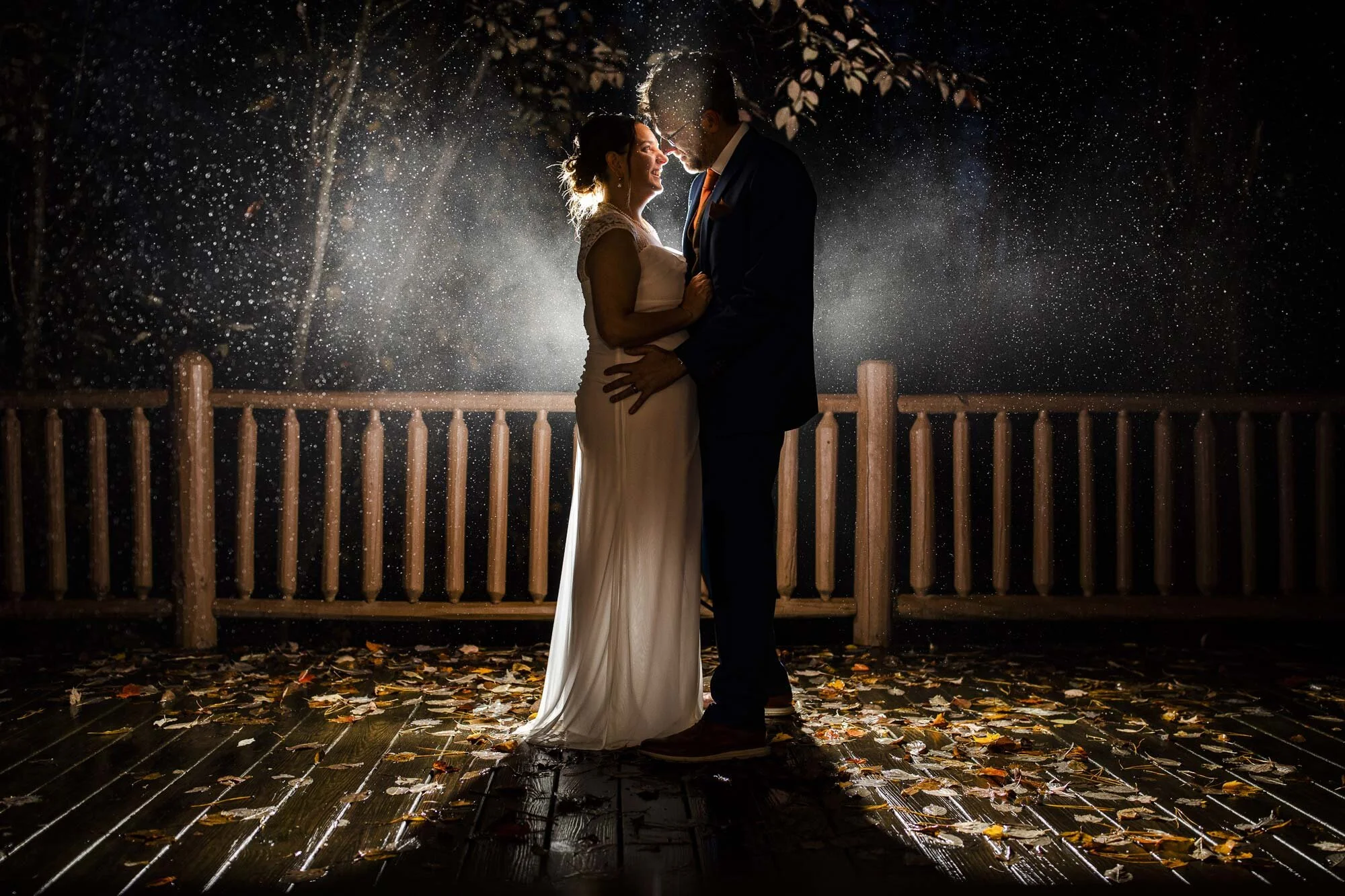 Newlywed couple in suit and dress lean in for kiss at night during rainy wedding in Ohio Amy Ann Photography