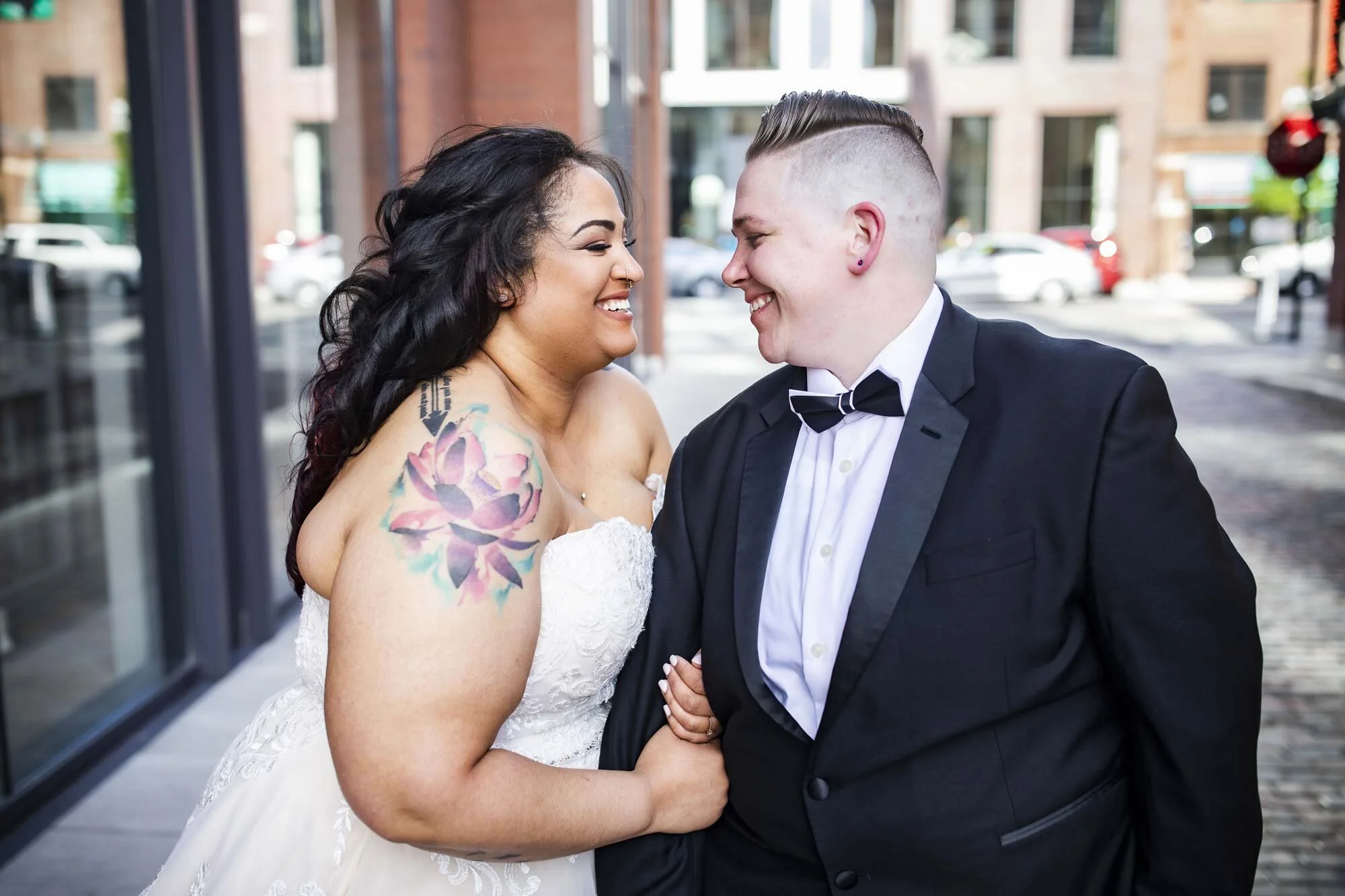 Newlywed couple smile at each other in dress and suit and walk down city sidewalk arm in arm before Ohio wedding ceremony Amy Ann Photography
