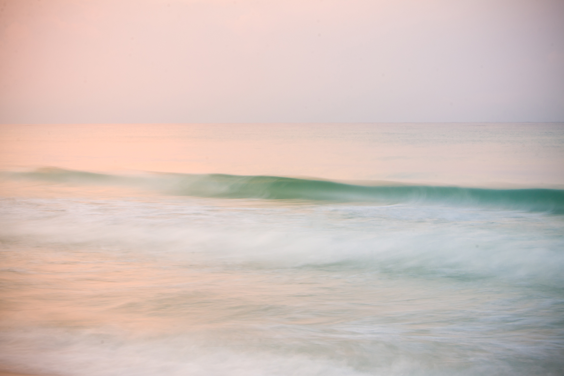 Colorful sunrise reflected in a moving wave.