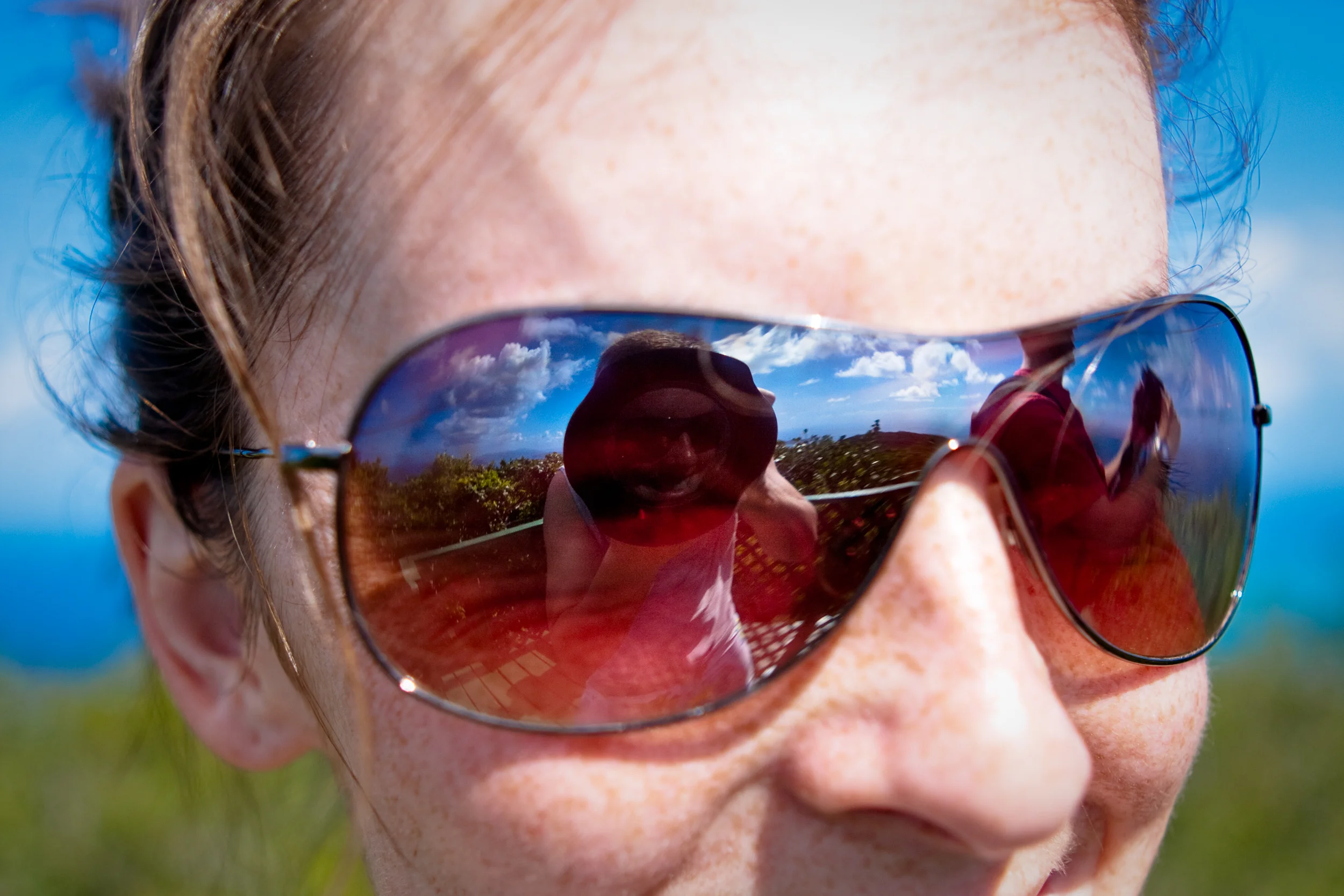 Clouds and blue sky reflection in sunglasses of a female adventurer.