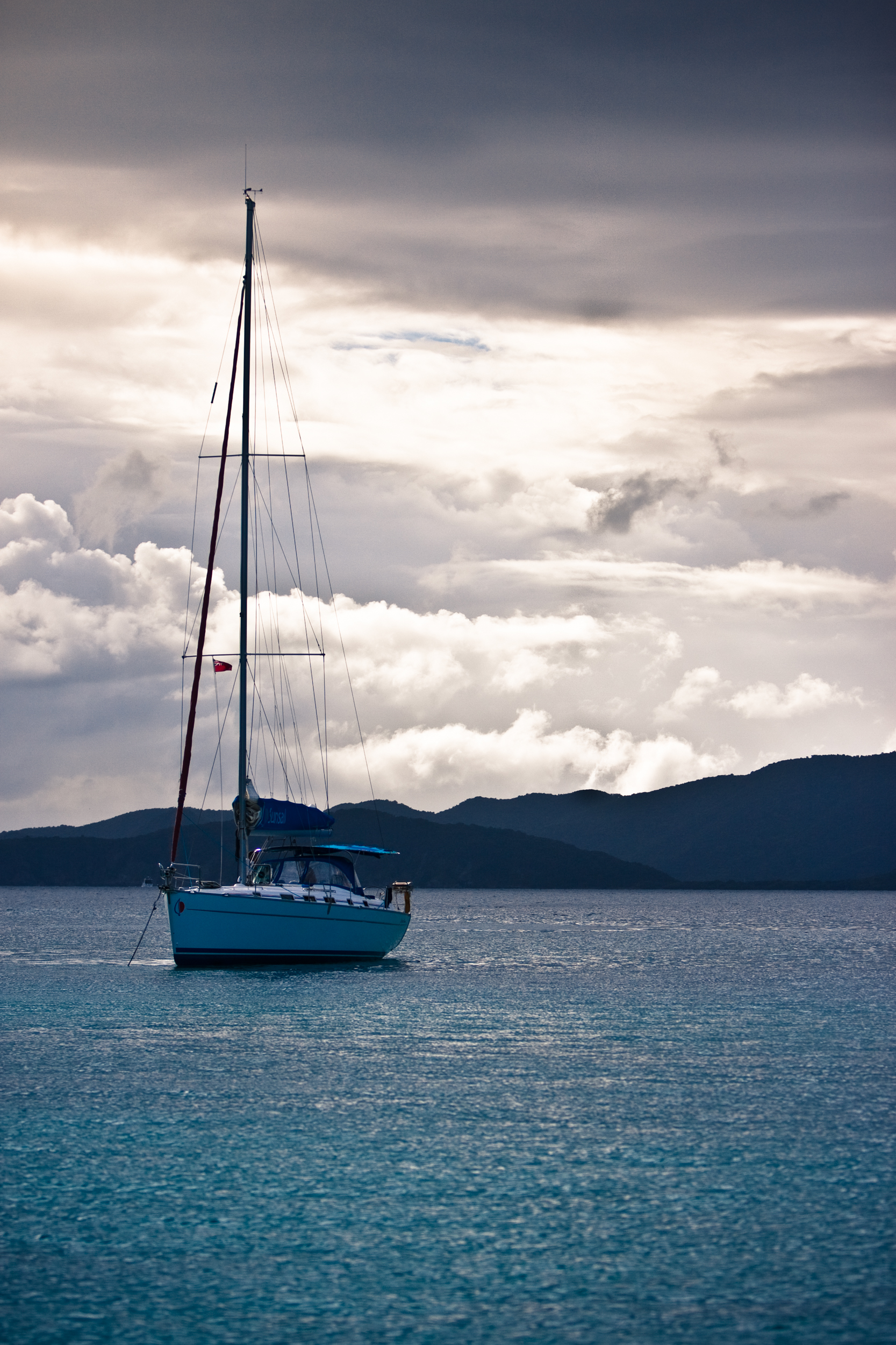 Anchored sailboat against a stormy sky of clouds.