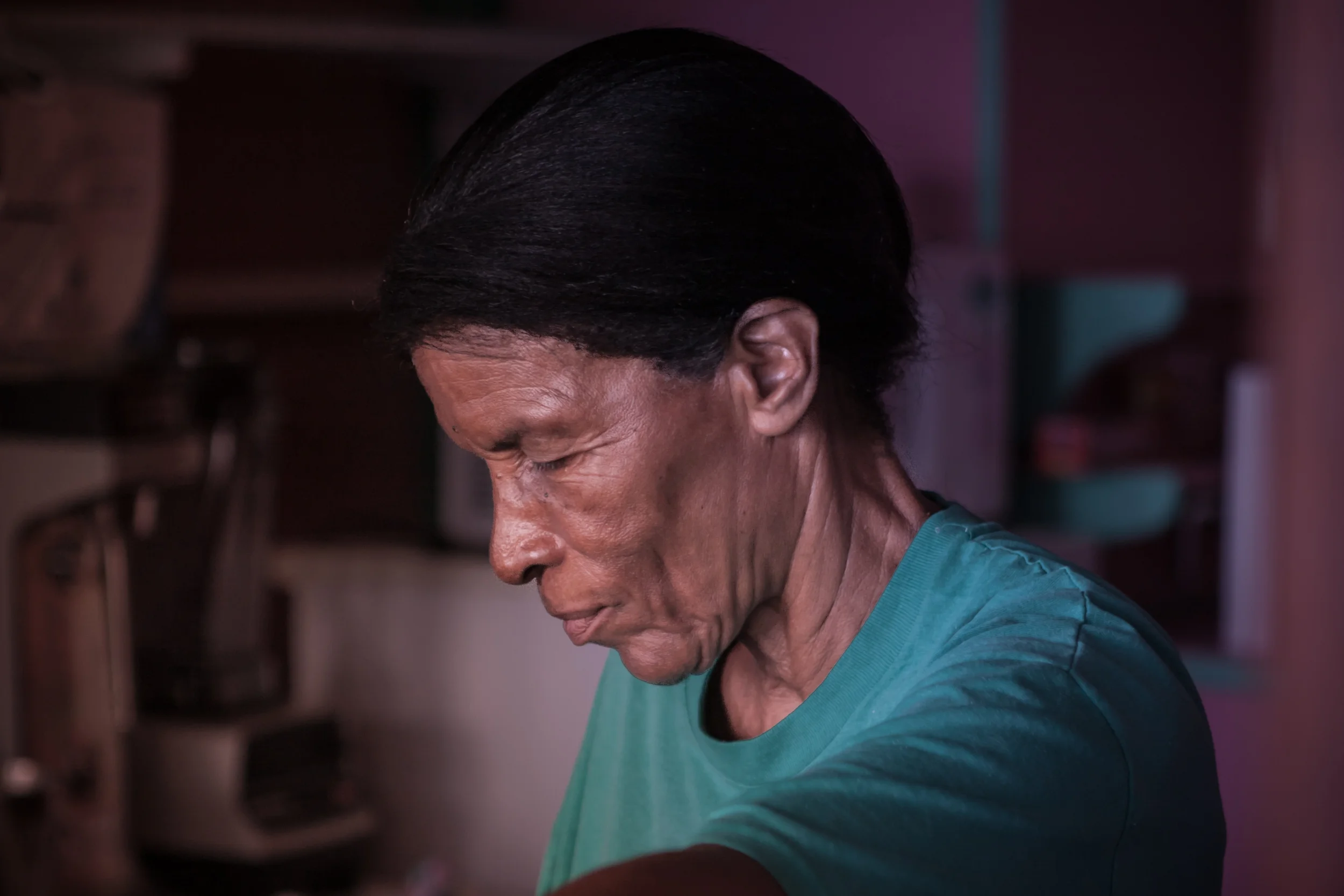 Portrait of an island native as she prepares food in a small pink kitchen.